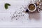 Teapot and dry tea leaves on white wooden background, green tea leaf on table, black herbal homemade hot beverage in porcelain pot