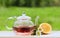 Teapot with fragrant herbal tea on a background of nature lemon