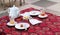 Teapot, glasses with leftover tea and dishes with leftover food and sugar on the table with a red tablecloth