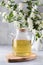 A teapot with green tea on the background of a branch with jasmine flowers. Chinese tea.