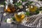 Teapot with herbal tea, cups with drink, scattered Jasmine flowers on gray surface