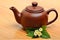 Teapot and jasmine flower twig on wooden background