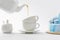 teapot pouring tea in cups near blue cake