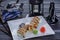 Teapot and sushi set with eel fish, nigiri, maguro and sushi rolls served on white plate on dark wooden background. Close up view.