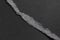 Tear of black paper sheet with ragged edges. Torn dark grey layered material