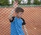 A tearful sad boy child tennis player stands behind a metal fence and looks downcast dejectedly. Losing Emotion in sport