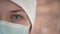 Tears in the eyes of a woman doctor in a medical mask, close-up. Tired doctor looks into the camera with feelings of