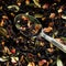 Teaspoon among black flavored tea with fruits, berries and flower petals. Macro. View from above. Photo
