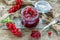 Teaspoon and glass jar with red currant jam.