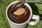 A teaspoon is pouring brown sugar into a cup of coffee, close up view.