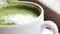 Teaspoon stirring matcha green tea latte in cup