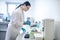 Technician in blue gloves pouring blood sample into the test tube and looking busy