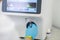Technician in blue gloves switching on hematological analyzer