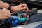 technician checks the battery using a voltmeter capacity tester,auto mechanic uses a multimeter voltmeter to check the voltage