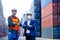 Technician or engineer workers stand in front of shipping container with one hold infrared thermometer and manager also wear face