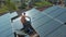 Technician with hard hat installing solar panel installed on home rooftop