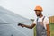 Technician in helmet using thermal imager on solar farm