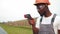 Technician in helmet using thermal imager on solar farm. Engineer in uniform measuring temperature of solar panels