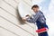 Technician Installing TV Satellite Dish On Wall