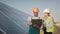 Technician and investor walking in Solar cell Farm through field of solar panels checking the panels at solar energy