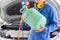 Technician with manifold tool gauge bucket refrigerant applies to car air conditioning, Repairman holding monitor tool to check