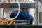 A technician in a medical mask works in a rack with computer equipment. The man serves the server room in the datacenter. Portrait