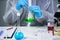 Technician in protective clothing hand stirring and shaking green liquid in Erlenmeyer flask in chemical laboratory. Laboratory