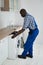 Technician Pulling Washing Machine In Kitchen