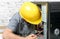 A technician repairing a computer with yellow helmet