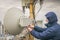 A technician is repairing a wireless data transmitter on the roof of a city building. A man performs maintenance and repair of a