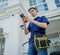 A technician sets up a CCTV camera on the facade of a residential building.