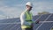 Technician walks beside array of solar panels