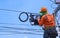 Technician on wooden ladder checking code numbers of fiber optic cable lines in internet splitter box for repairing on power pole