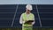 Technician writing on clipboard while examining solar panels.