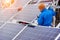 Technicians in blue suits mounting photovoltaic solar panels on roof of modern house.