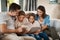 Technology connects us with family in more ways than one. a young family of four reading a book together on the sofa at