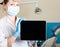 Technology, internet and networking in medicine concept - femail dentist holding a tablet pc with a blank dark screen