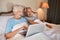 Technology makes it easier to share photographs. a happy senior woman using a laptop and sitting in bed with her husband