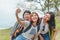 Technology, travel, tourism, jungle hike and people concept - group of smiling friends with backpacks taking selfie by smartphone