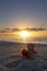 Teddy bear on a beach at sunrise with flowers