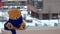 Teddy bear with blue scarf is sitting by window in winter. Snowflakes falling