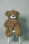 Teddy Bear. Brown teddy bear on gray background. A plush brown shot in a photo studio on a bar stool. A toy. Childhood