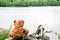 Teddy bear fisherman. Brown teddy bear sits by the lake with a fishing rod and catches fish