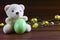 Teddy Bear holding an Easter egg, chicken, wood background