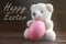 Teddy Bear holding an Easter egg, chicken, wood background