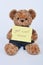 Teddy bear holding a yellow sign saying Get Well Soon isolated on white background