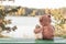Teddy bear hugs toy bunny on bench on riverbank in autumn