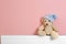 Teddy bear with knitted hat on heating radiator near color wall