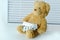 Teddy bear, medications, white pills in a blister, against the background of blinds on the table, concept getting sick, having a