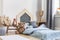 Teddy bear next to a bed covered with blue sheets in a natural kid room interior. Real photo